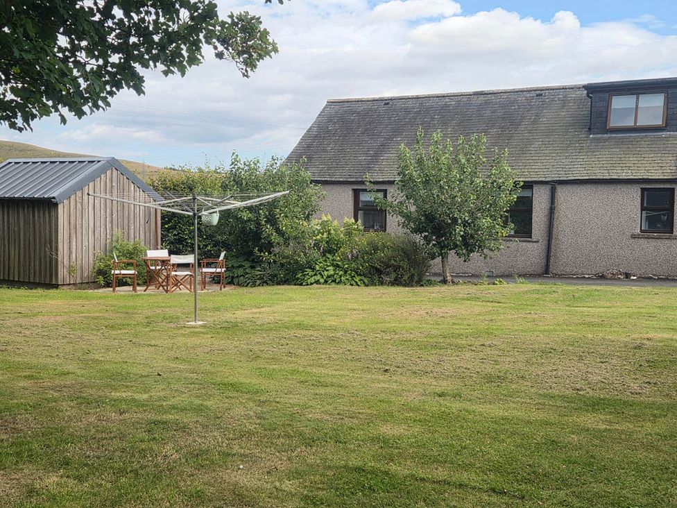 A garden with a house, shed, table, and chairs at Farm Cottage at foot Angus Glens Kirkton of Kingoldrum near Kirriemuir