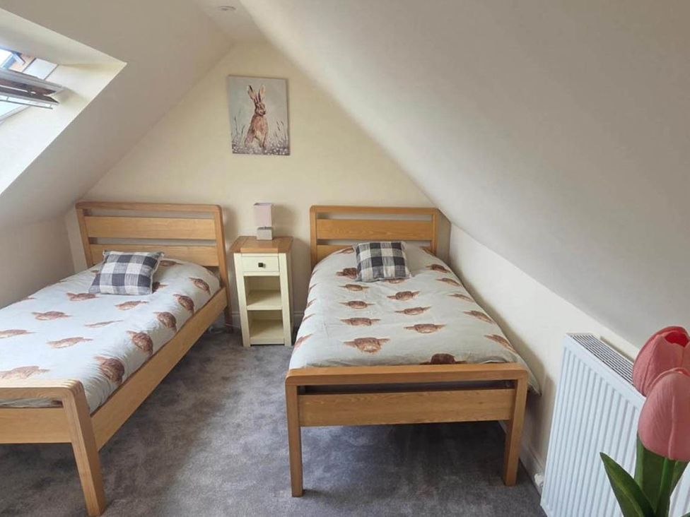 A bedroom with two beds and a nightstand at Farm Cottage at foot Angus Glens Kirkton of Kingoldrum near Kirriemuir