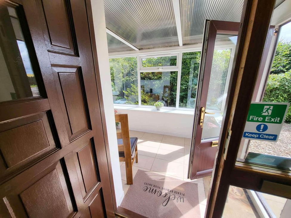 A conservatory view with a door and chair at Farm Cottage at foot Angus Glens Kirkton of Kingoldrum near Kirriemuir