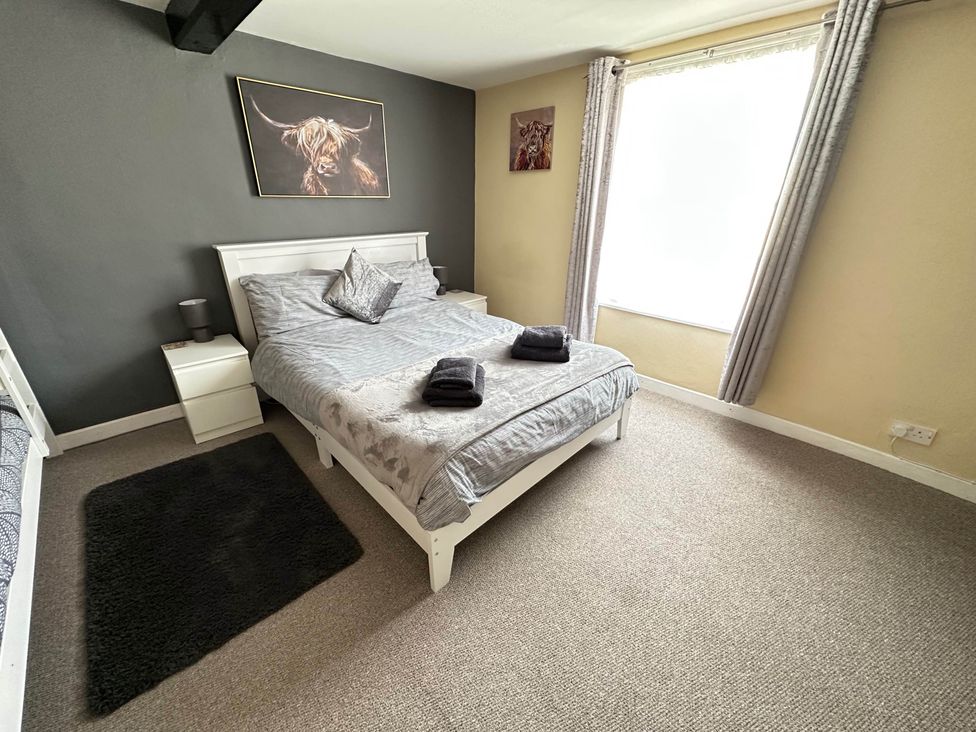 A bedroom with a bed and bedside table at Llanidloes - Sleeps 7 - Parking - Pet Friendly, Llanidloes