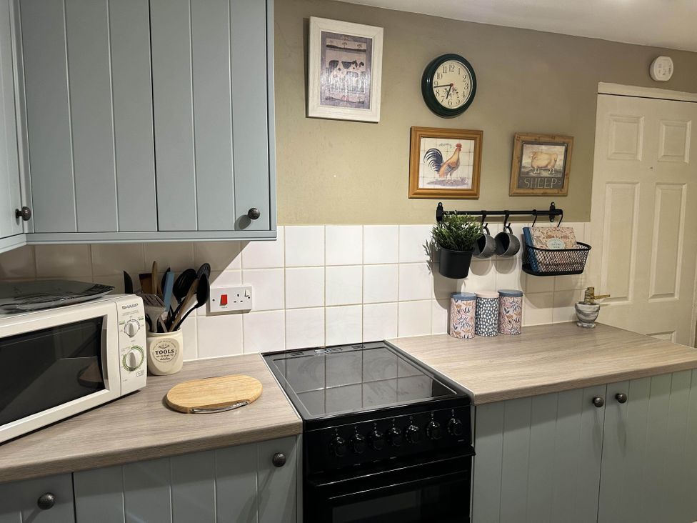 A kitchen with microwave, oven, and utensils holder at Llanidloes - Sleeps 7 - Parking - Pet Friendly, Llanidloes