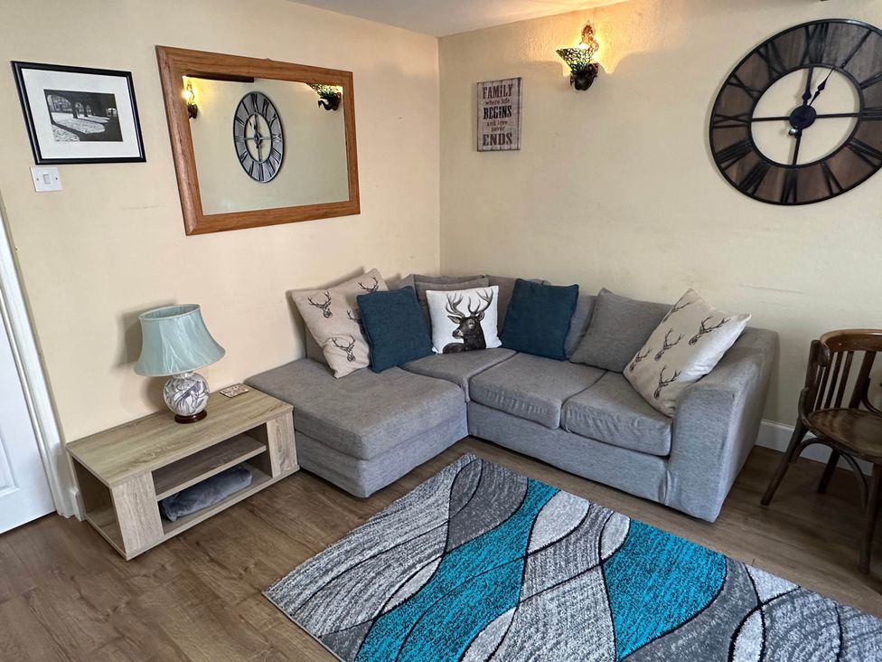 A living room with a sofa and a clock at Llanidloes - Sleeps 7 - Parking - Pet Friendly, Llanidloes