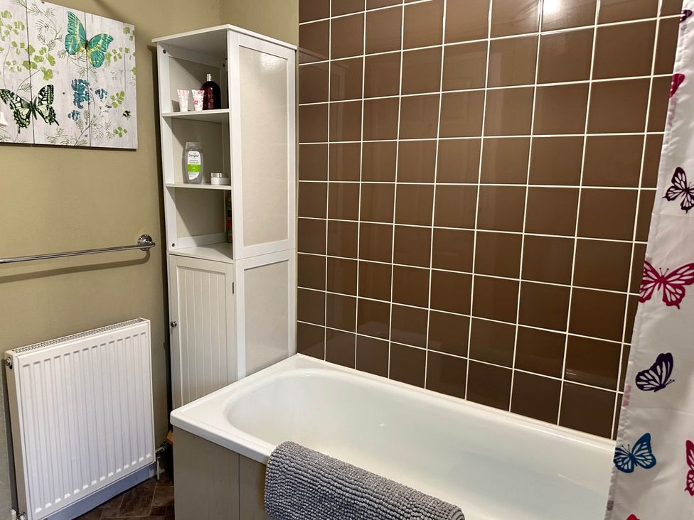 A bathroom with a bathtub and shelf at Llanidloes - Sleeps 7 - Parking - Pet Friendly, Llanidloes