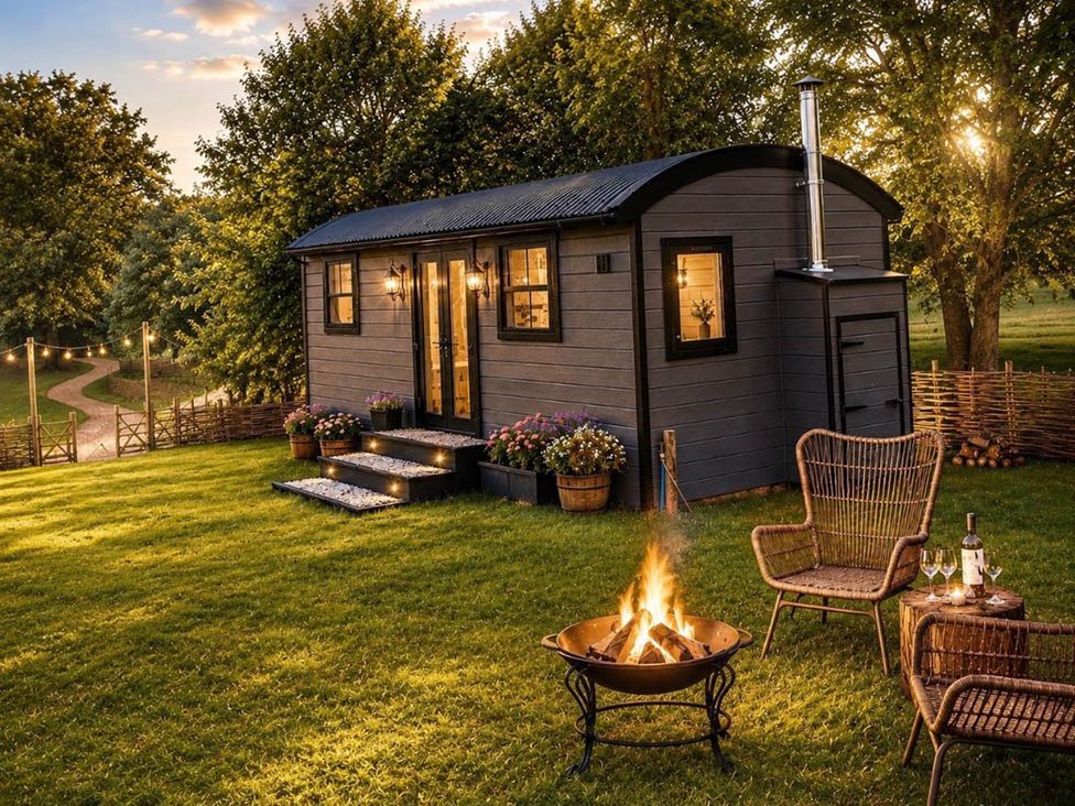 A shepherd hut with a fire pit and outdoor chairs at Peaceful Shepherd Hut near Clovelly