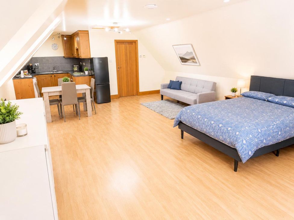 A living room with a bed and kitchen area at Surridges Studio, Sleeps 4 w/ Parking & Dogs Ok, Latchingdon near Burnham-On-Crouch