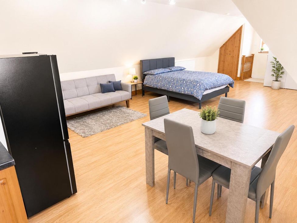 A living room with a sofa, bed, table and chairs at Surridges Studio, Sleeps 4 w/ Parking & Dogs Ok in Latchingdon near Burnham-On-Crouch