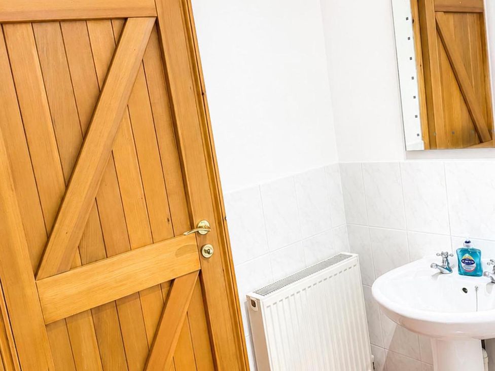 A bathroom with a wooden door and sink at Surridges Studio, Sleeps 4 w/ Parking & Dogs Ok, Latchingdon near Burnham-On-Crouch