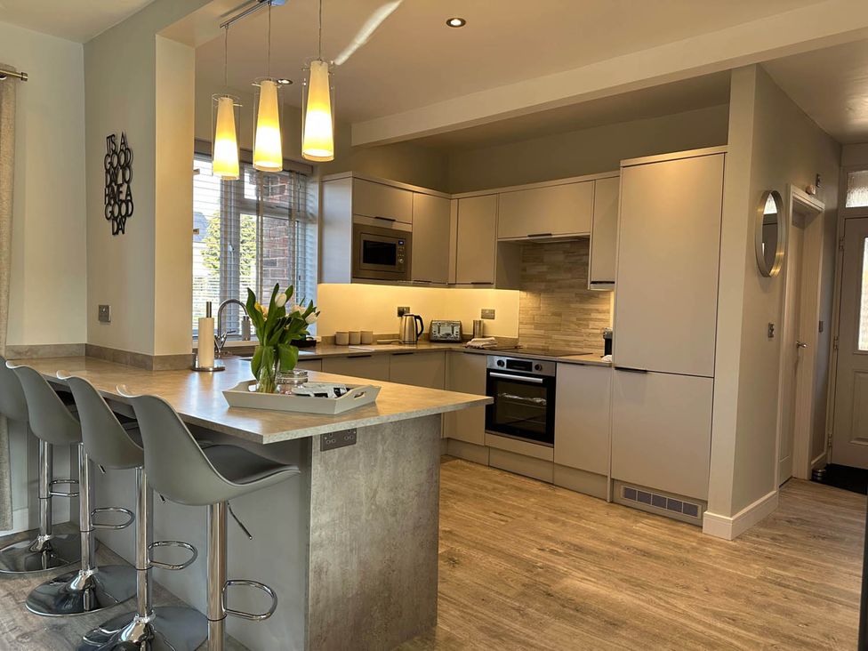 A kitchen with an island and stools at Stylish Home Sleeps 4 Free Parking Earl Shilton