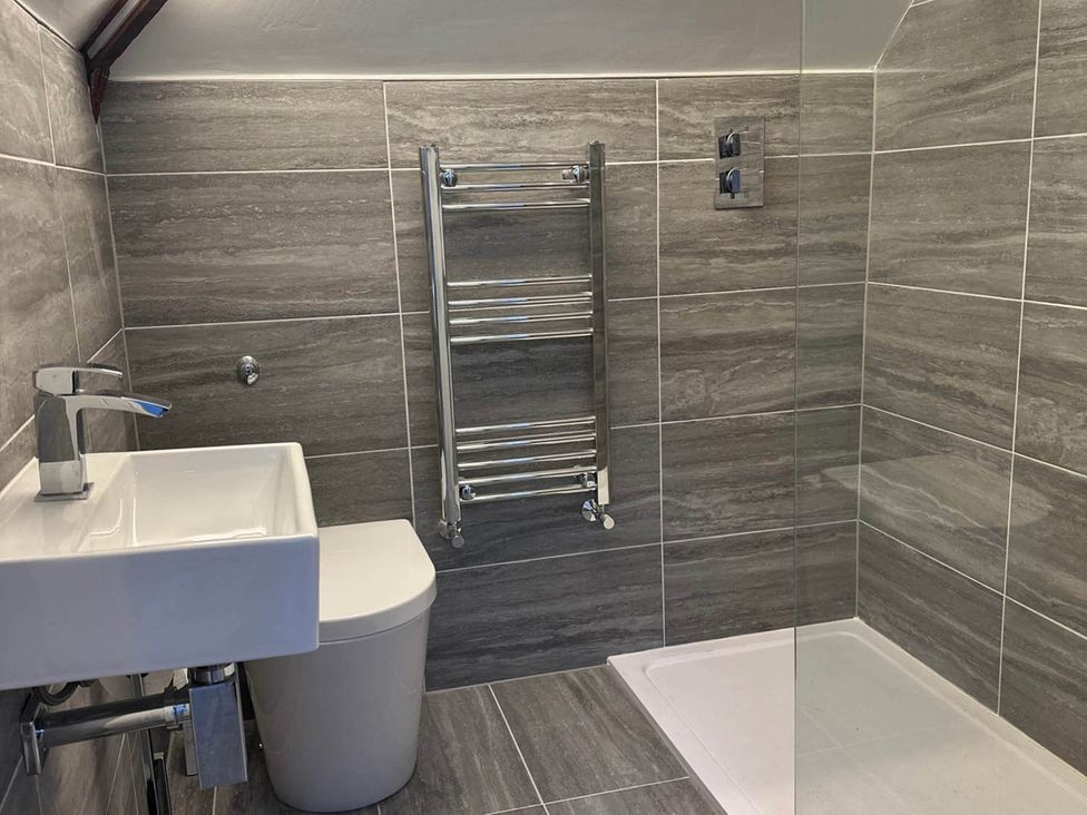 A bathroom featuring a wash basin, toilet, towel radiator, and shower enclosure at Stylish Home Sleeps 4 Free Parking Earl Shilton