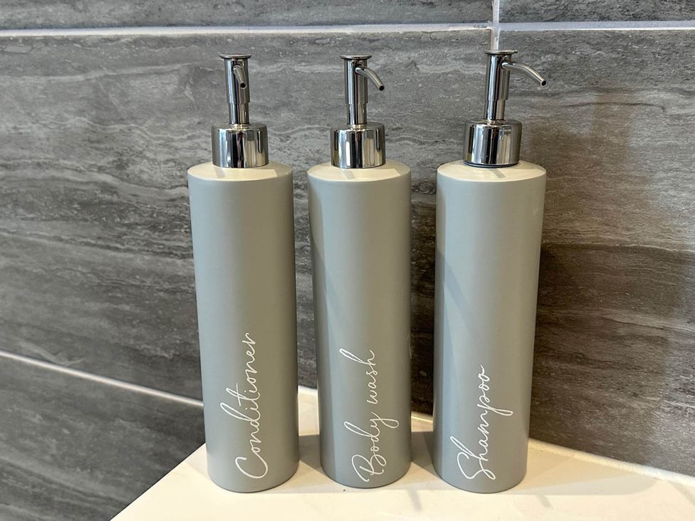 Three bottles labeled conditioner, body wash, and shampoo in a bathroom