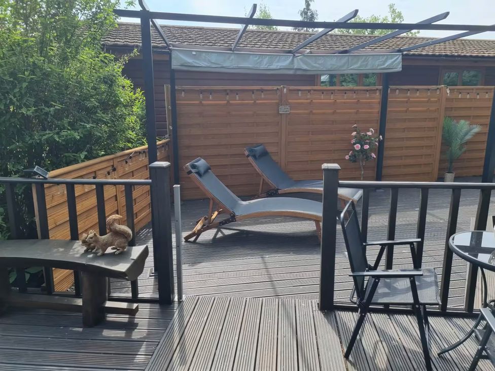 An outdoor area with lounge chairs and a table at Cabin Sleeps 4 with Hot Tub and Parking Near Wilberfoss