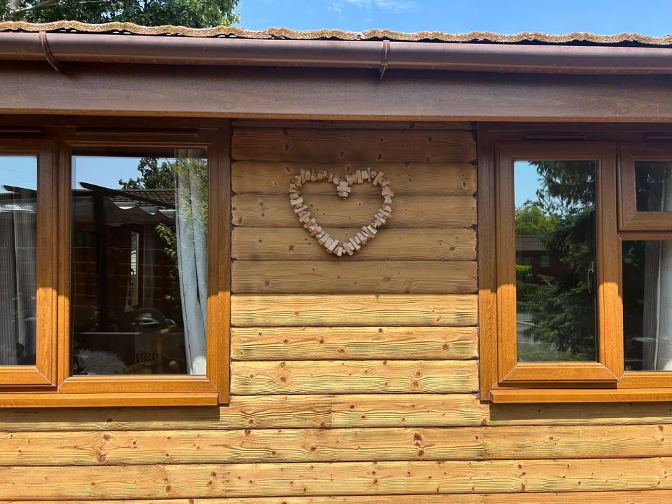 A wooden exterior wall with windows and a heart decoration at Cabin Sleeps 4 with Hot Tub and Parking near Wilberfoss