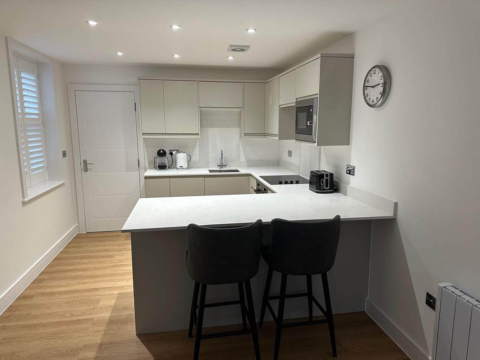 A kitchen with bar stools and appliances at 59 Whitstable - One Bedroom Ground Floor Flat in Whitstable