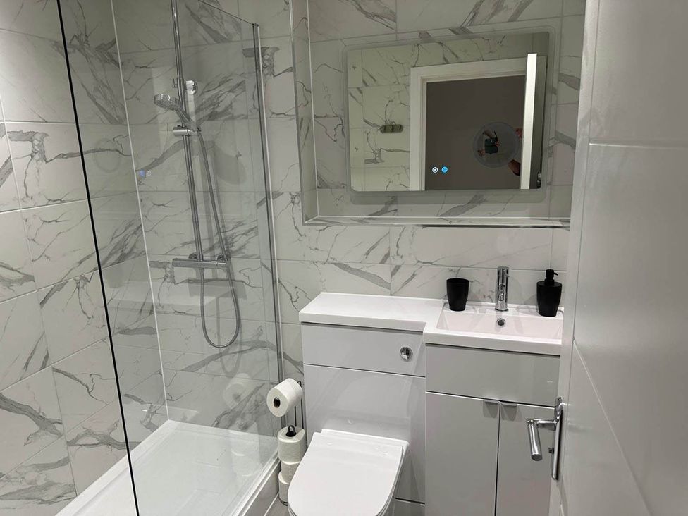 A bathroom with a shower, toilet, sink, and mirror at 59 Whitstable - One Bedroom Ground Floor Flat