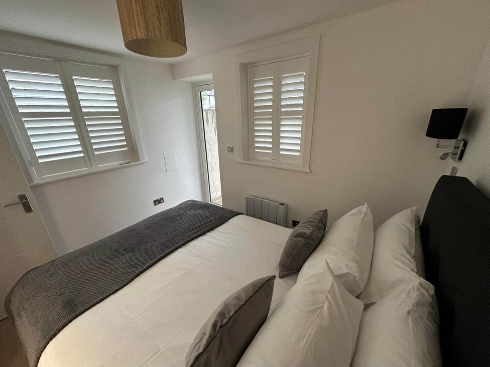 A bedroom with a bed and windows at 59 Whitstable - One Bedroom Ground Floor Flat