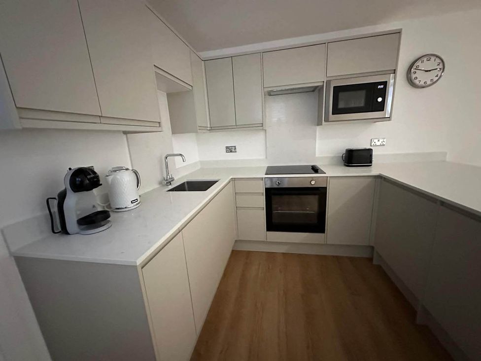A kitchen with cabinets, sink, oven, microwave, kettle, and coffee maker at 59 Whitstable - One Bedroom Ground Floor Flat in Whitstable