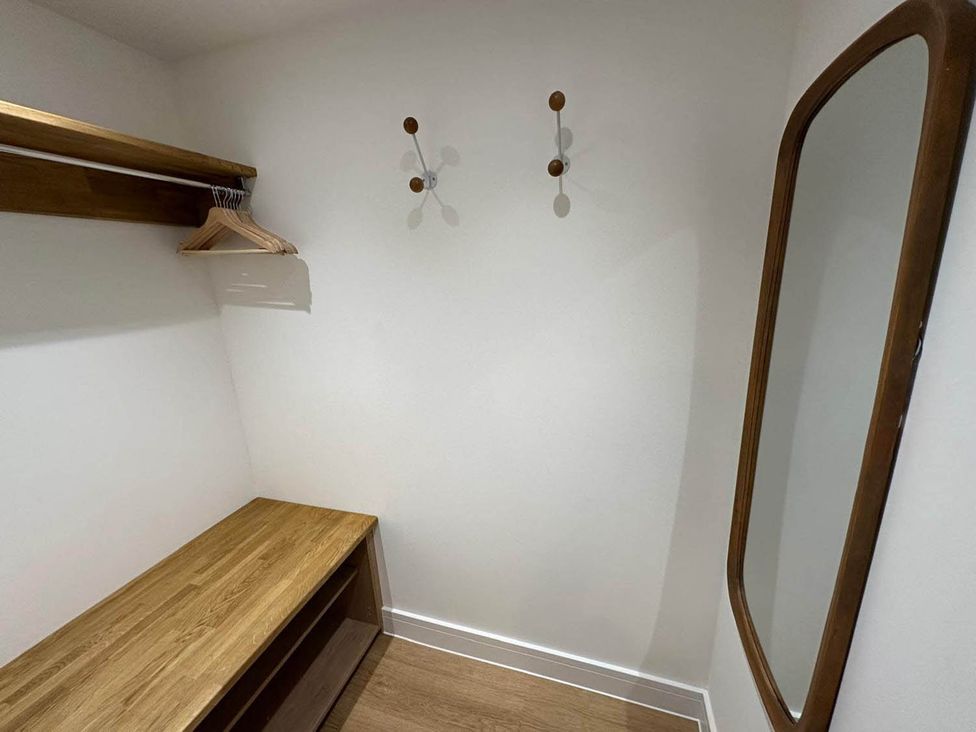 A closet with a mirror, shelf, bench, and coathooks at 59 Whitstable - One Bedroom Ground Floor Flat, Whitstable