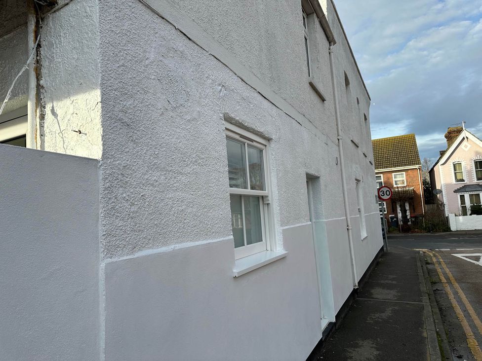 A side of a building with windows and a street sign at 59 Whitstable - One Bedroom Ground Floor Flat in Whitstable