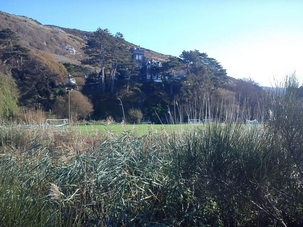 A house on a hill overlooking a grassy field with goal posts in Barmouth