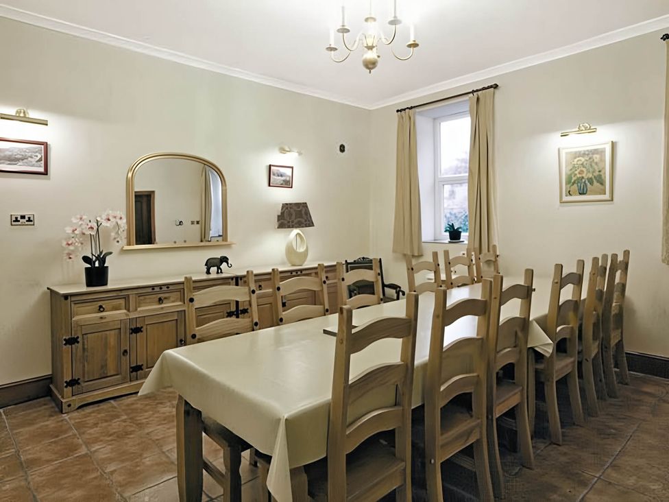A dining room with a long table and chairs at The Old Barn in Barmouth