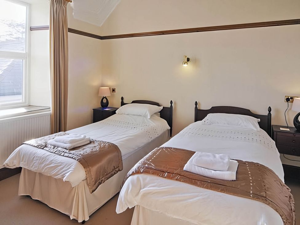 A bedroom with two single beds and a window at The Old Barn in Barmouth