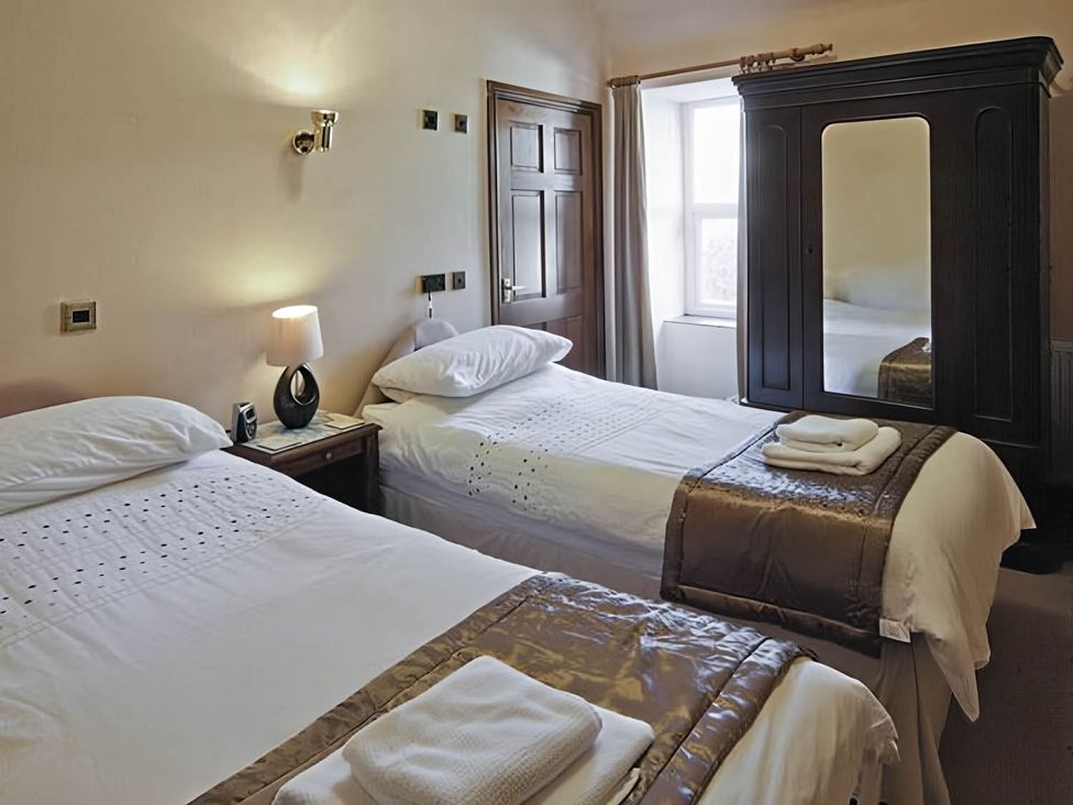 A bedroom with two beds and a wardrobe at The Old Barn in Barmouth