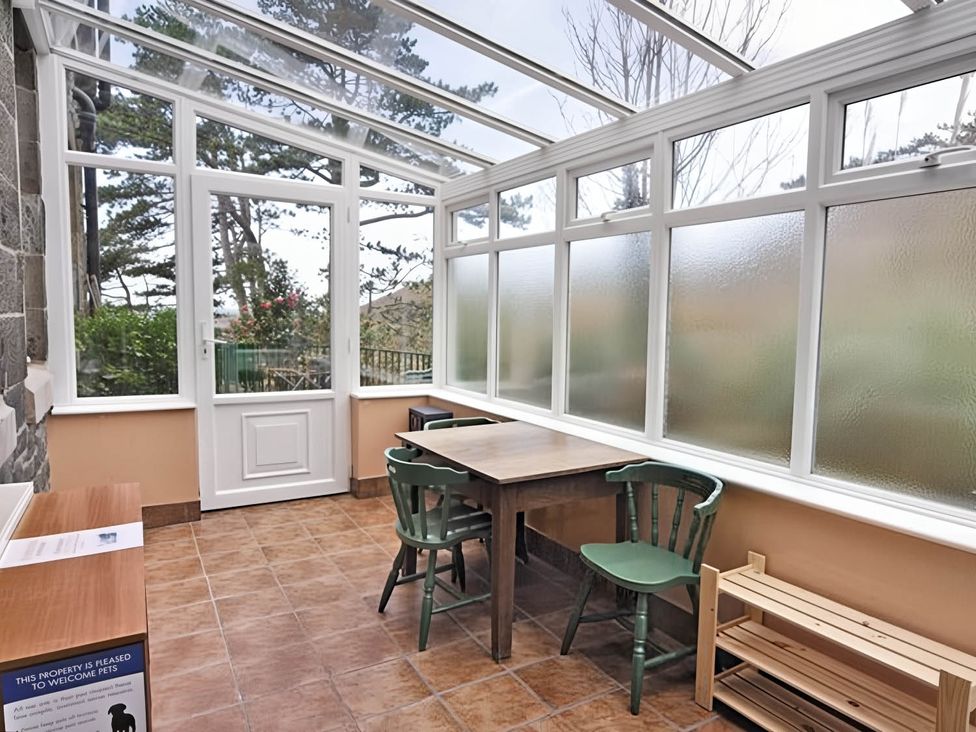 A conservatory with a table and chairs at The Old Barn in Barmouth