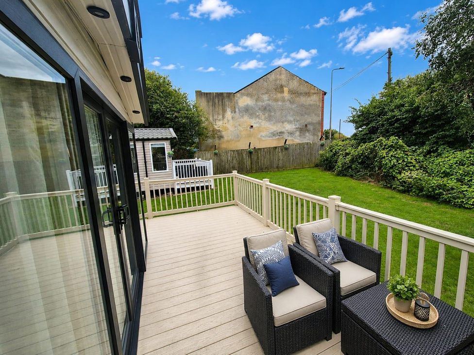 A decking area with seating and garden at Cala Gran 3Bed Caravan Sleeps 8 Wrap Decking, Fleetwood
