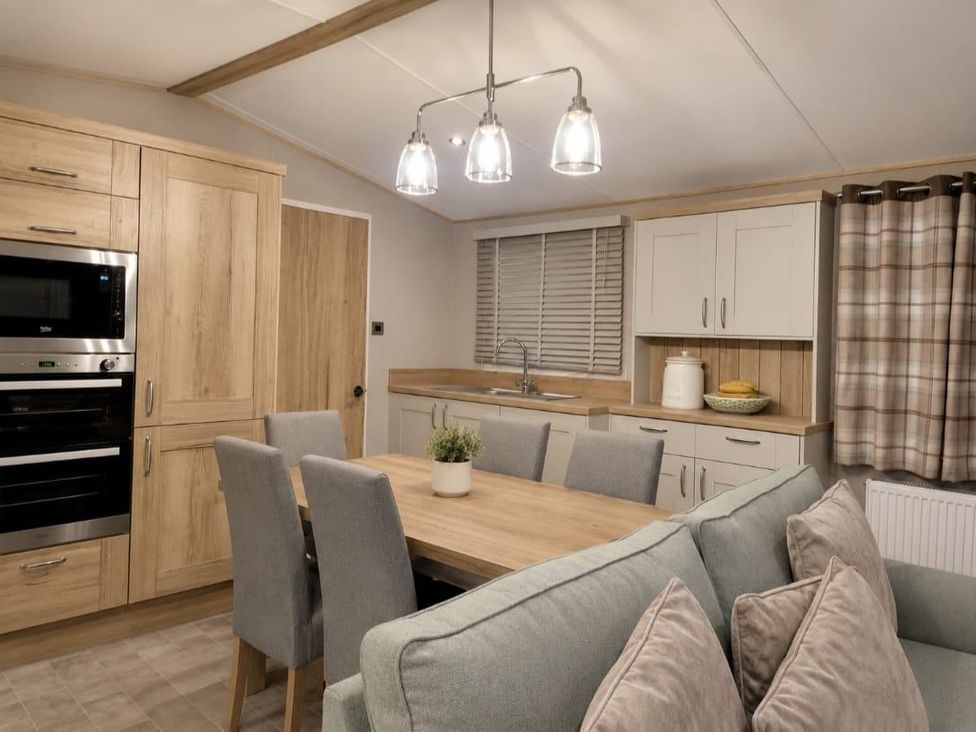 A kitchen with a dining table and appliances at Cala Gran 3Bed Caravan Sleeps 8 Wrap Decking Fleetwood