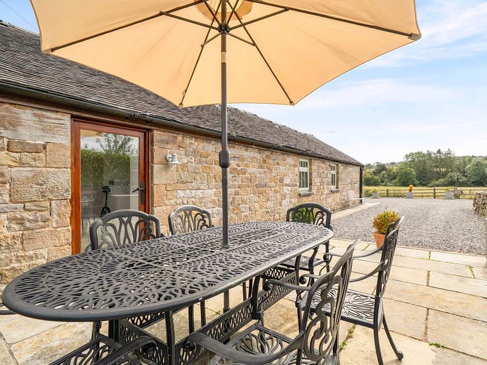 An outdoor patio with a table and umbrella at the property near Waterhouses