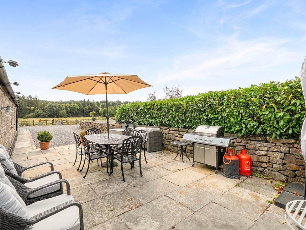 An outdoor patio with a table and chairs at The Old Barn Near Waterhouses