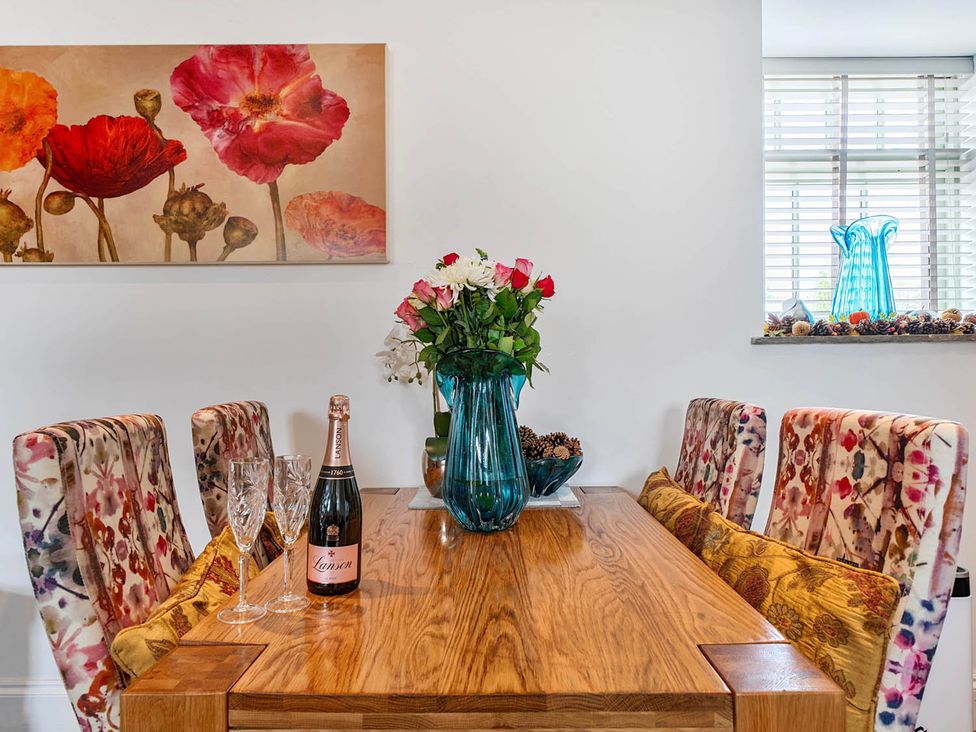 A dining room with a wooden table and flowers at The Old Barn Near Waterhouses