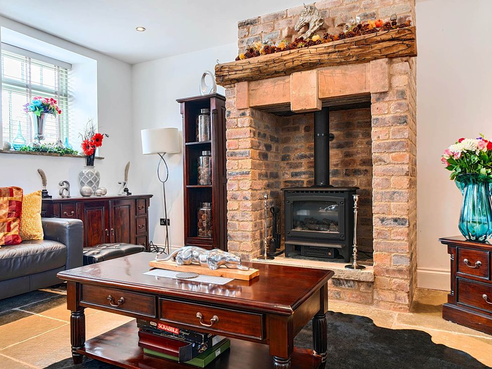 A living room with a fireplace and wooden furniture at The Old Barn near Waterhouses