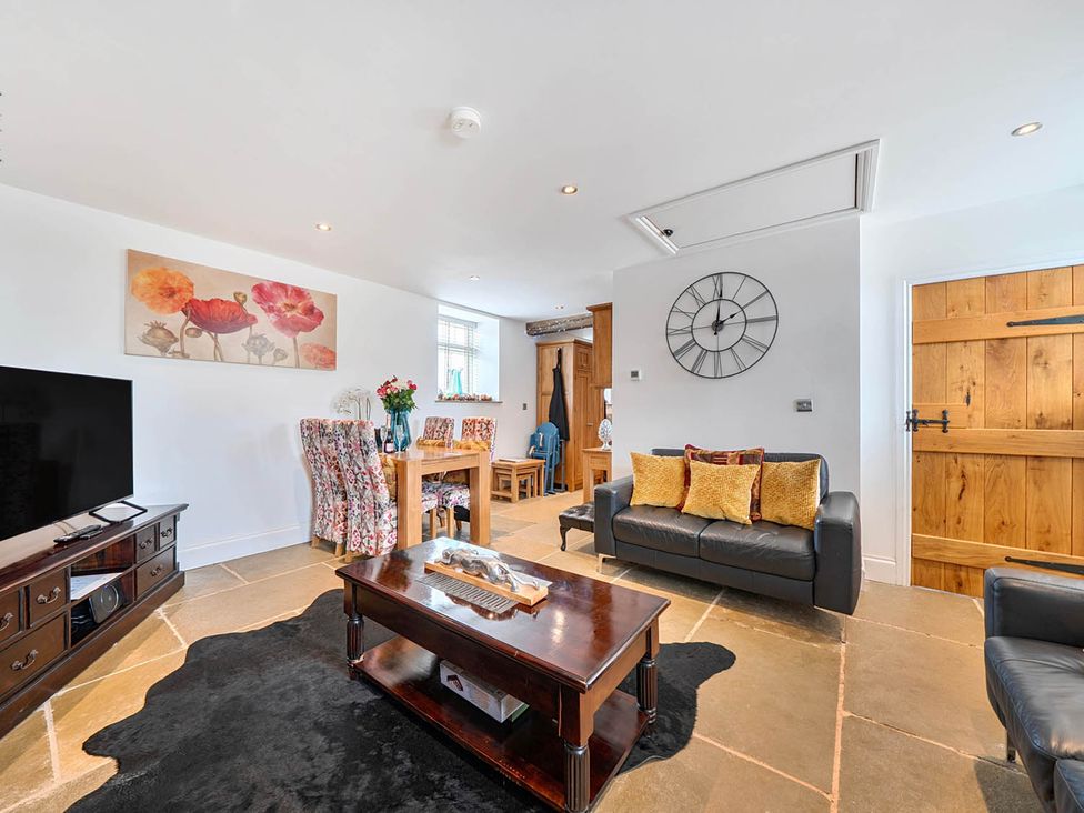A living room with a sofa and dining table at The Old Barn Near Waterhouses