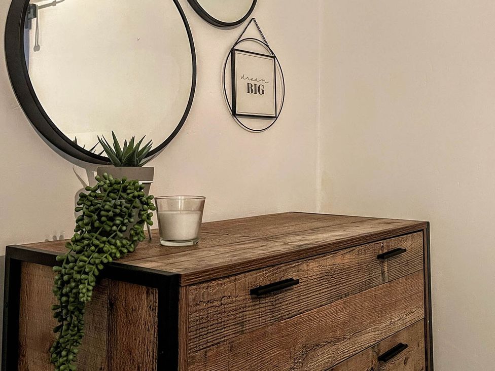 A chest of drawers with a plant and candle in an indoor setting at 
