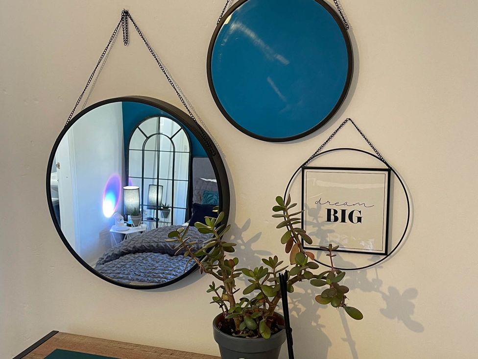 A collection of mirrors and wall art above a plant at The Old Barn in Bradworthy