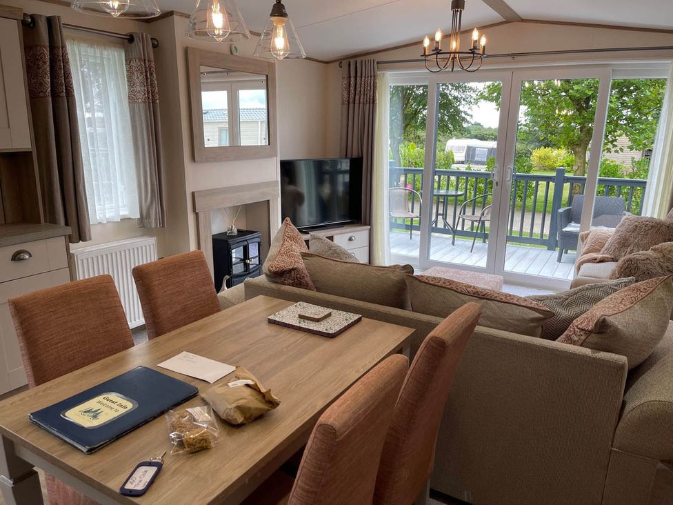 A living room with a dining table and a sofa with a view of the deck at the property in location