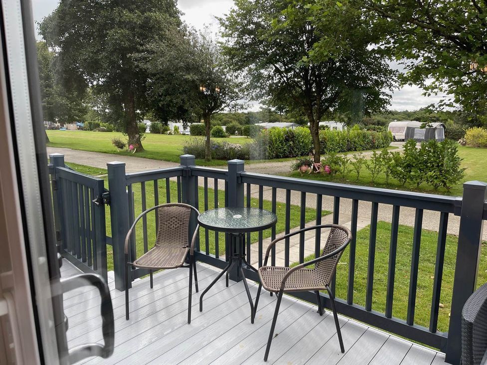 A deck with chairs and a table looking at a garden area at The Retreat in unknown location