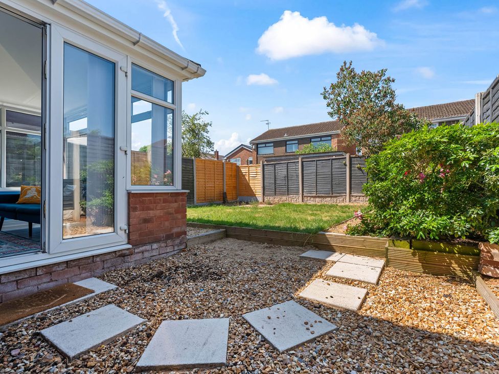 A garden with a conservatory and pathway at The Old Barn in Stafford