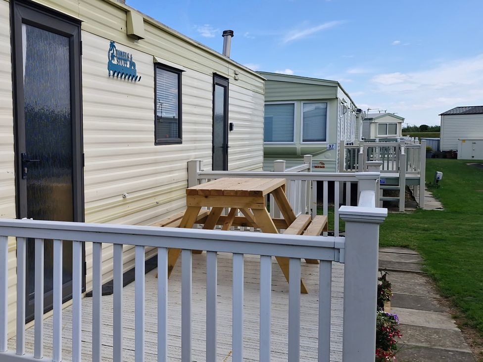 An outdoor area with a table and chairs in front of a mobile home at Anderby Creek