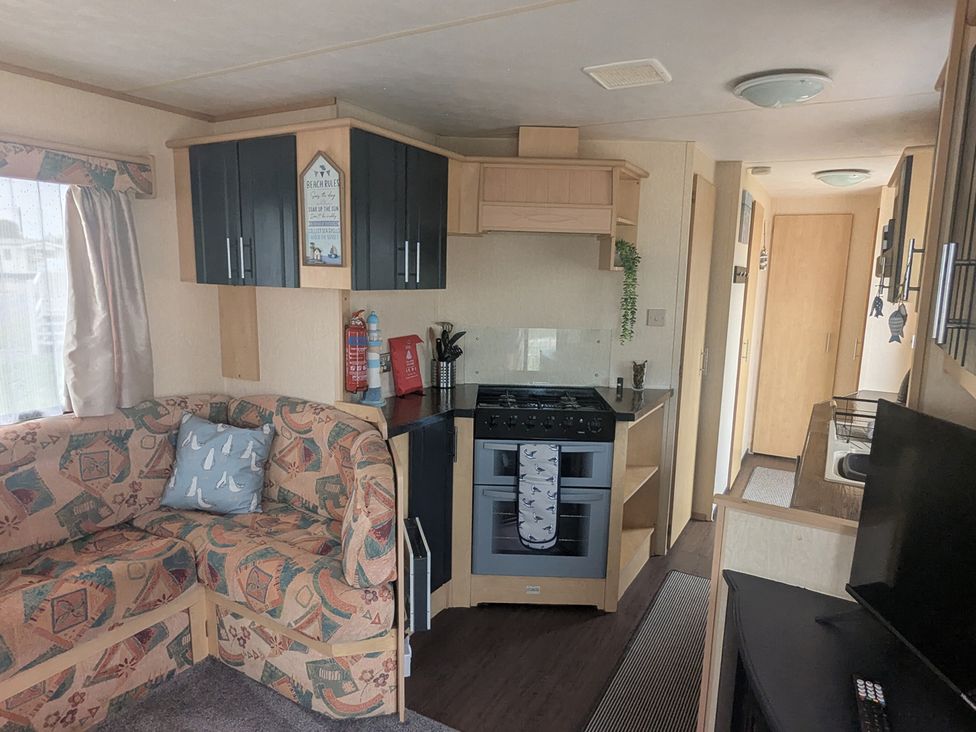 A kitchen with a stove and sofa at The Old Barn in Anderby Creek
