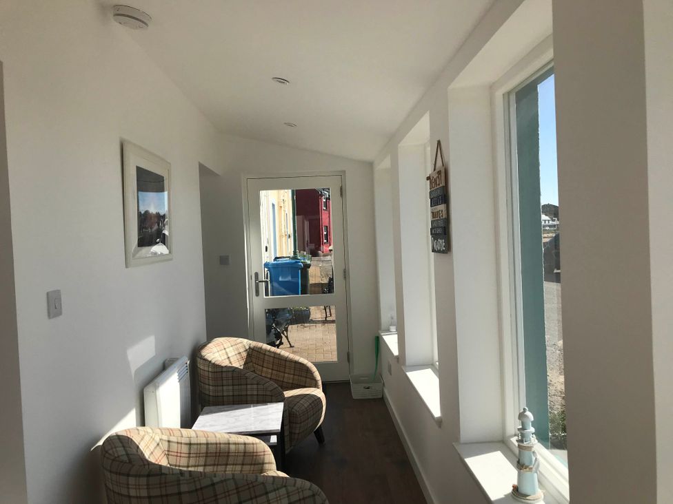 A hallway with two chairs and a table at PetFriendly Beachfront Sunset Facing Porch Garden in Portmahomack