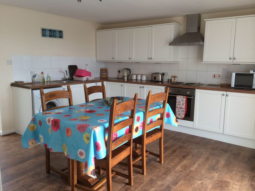 A kitchen with a table and chairs at PetFriendly Beachfront Sunset Facing Porch Garden in Portmahomack