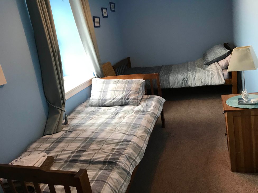 A bedroom with two beds and a nightstand at PetFriendly Beachfront Sunset Facing Porch Garden in Portmahomack