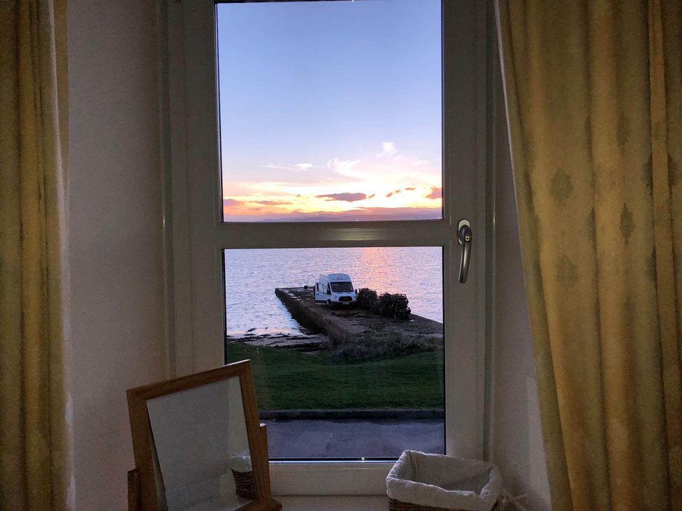 A window view showing a van by the water at PetFriendly Beachfront Sunset Facing Porch Garden in Portmahomack