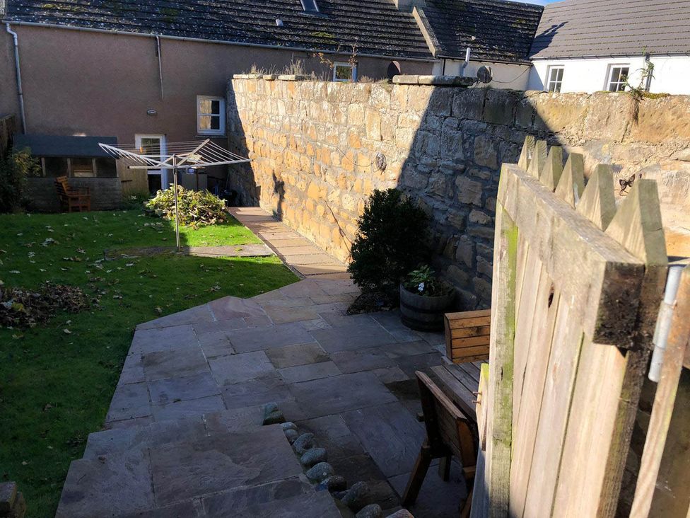 A garden with a stone wall and lawn area at PetFriendly Beachfront Sunset Facing Porch Garden in Portmahomack