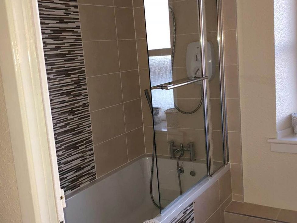 A bathroom with bathtub and shower at PetFriendly Beachfront Sunset Facing Porch Garden in Portmahomack
