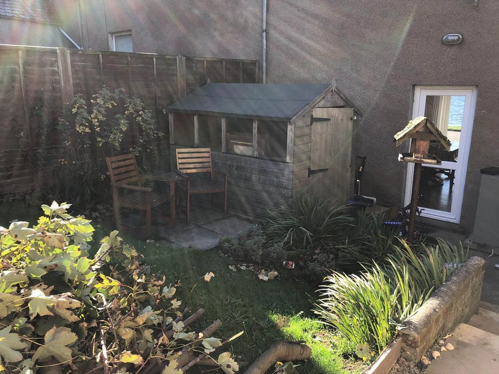 A garden with a wooden shed and chairs at PetFriendly Beachfront Sunset Facing Porch Garden in Portmahomack