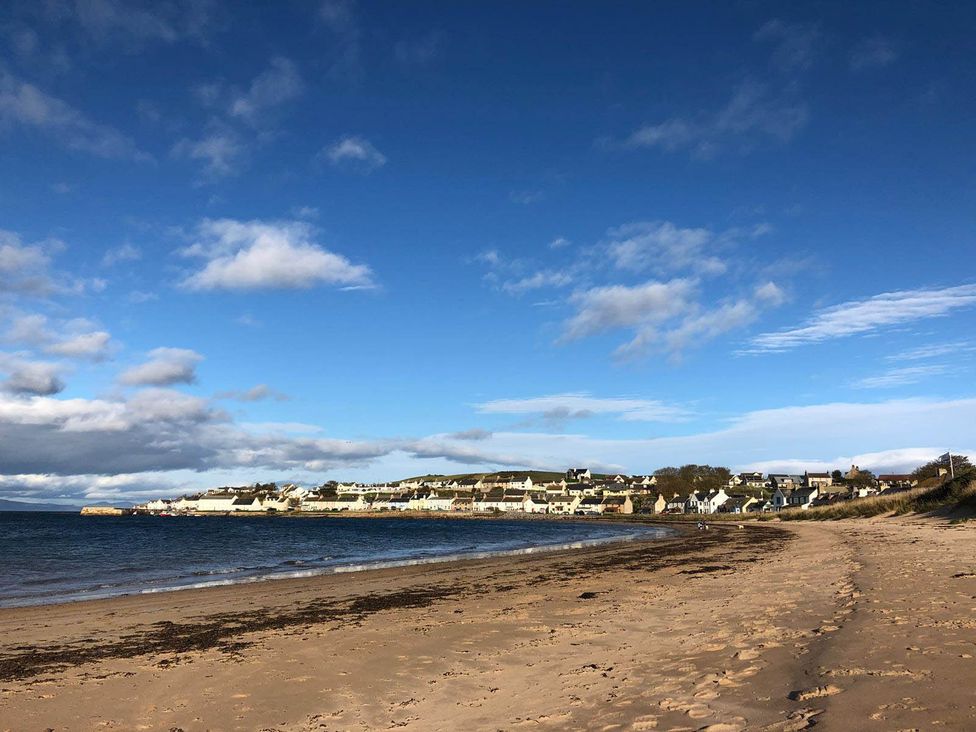 A beach with sand and water near houses at PetFriendly Beachfront Sunset Facing Porch Garden Portmahomack