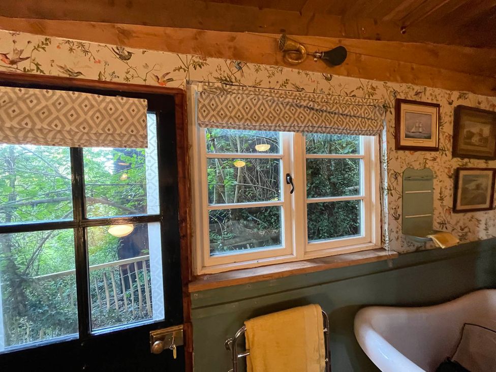 A bathroom with a window and bathtub at The Old Barn in Bovey Tracey